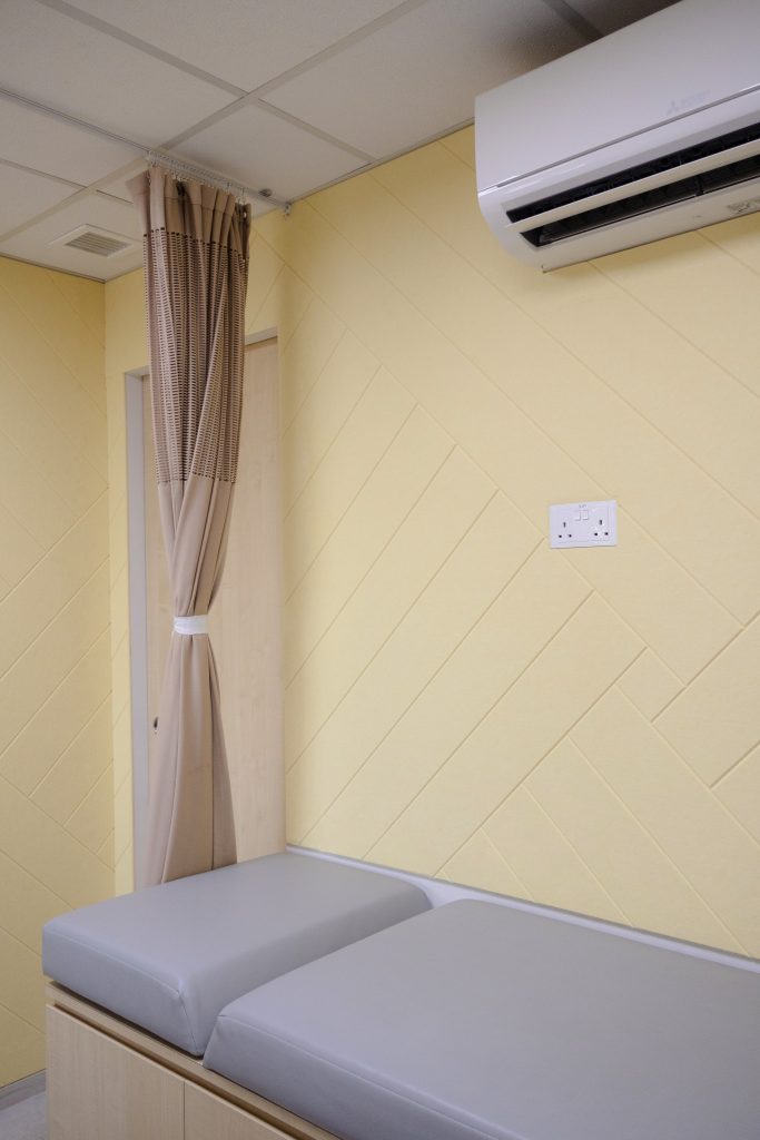 Grooved acoustic panels in Canary finish installed on clinic wall for sound reflection control