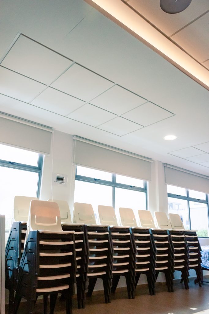 White acoustic ceiling panels installed around lighting and air-conditioning units in church space for seamless acoustic treatment