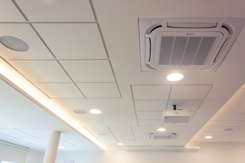 Clean white ceiling panels forming a continuous surface despite lighting and ventilation interruptions