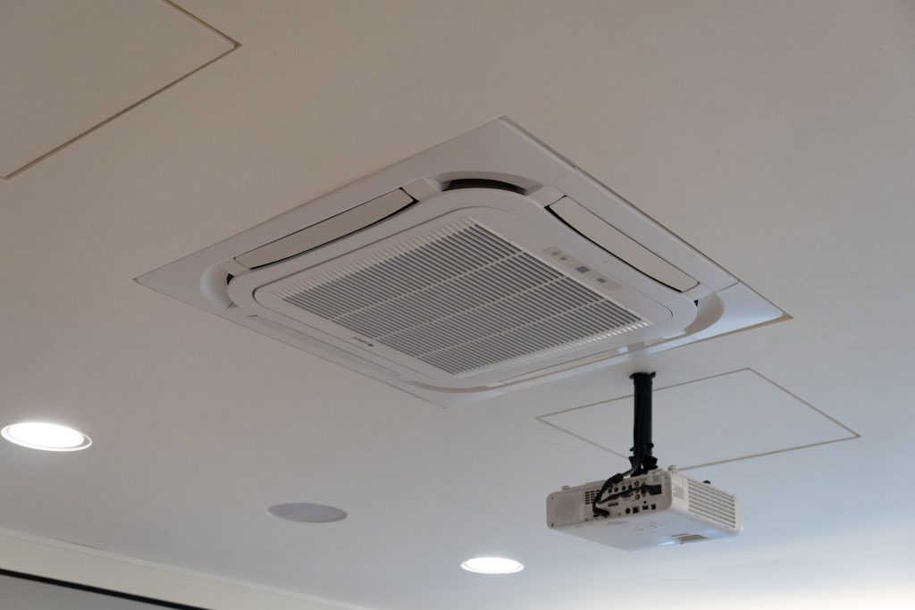 White acoustic ceiling panel layout fitted around lighting and air-conditioning units in church space
