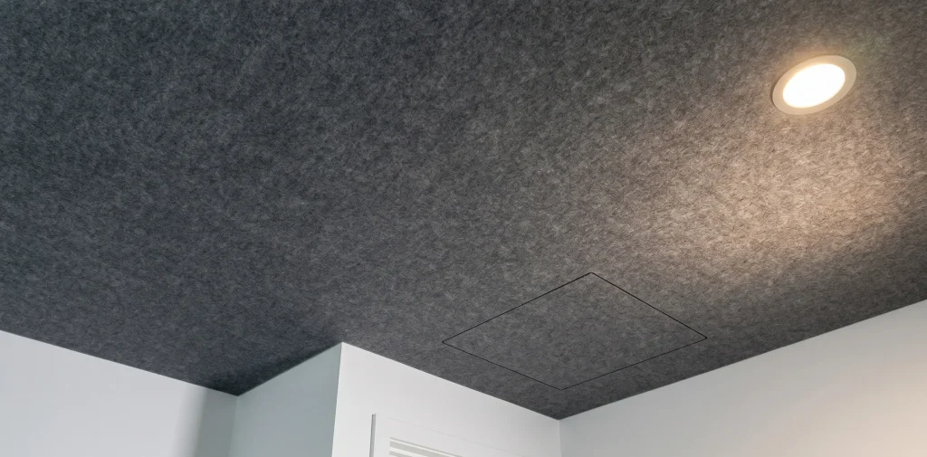 Dark grey acoustic ceiling panels with a seamless finish installed across the ceiling surface.