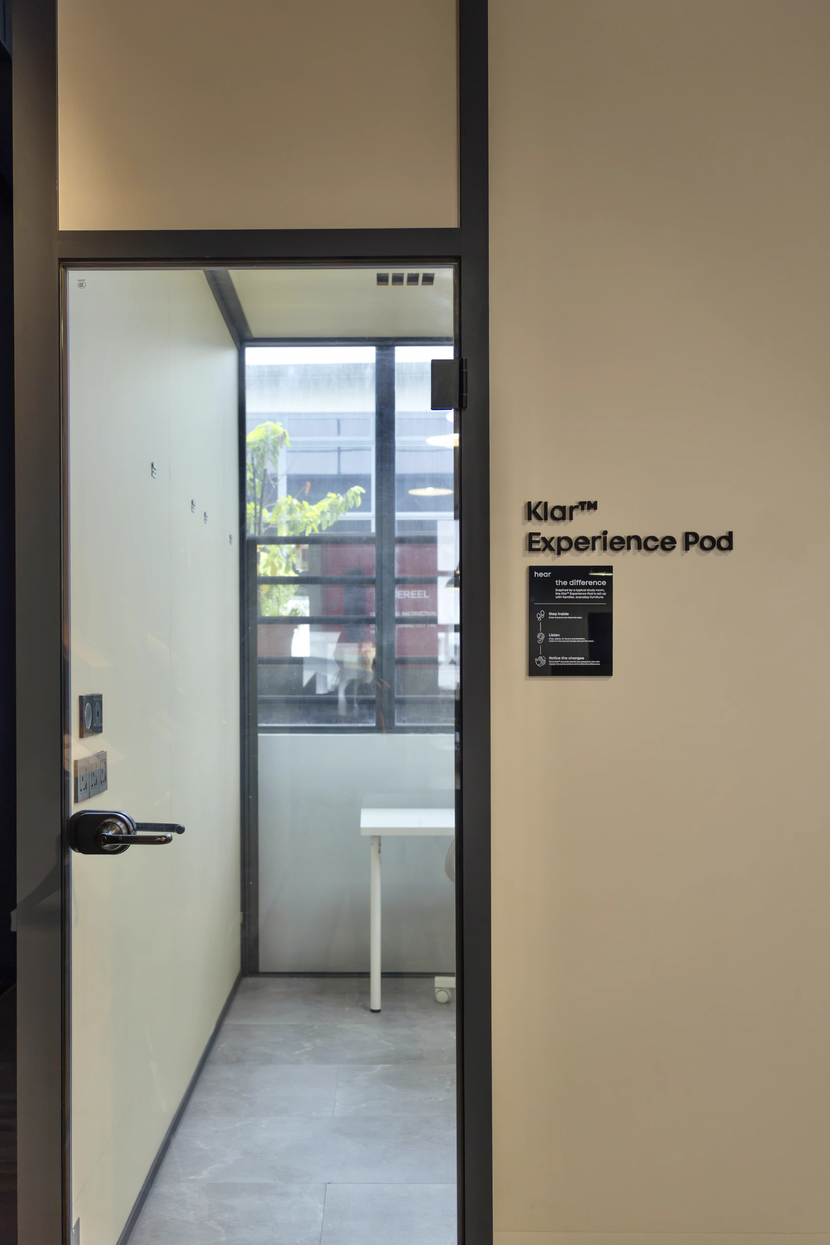 Glass door opening into the Klar™ Experience Pod, a small study room for hearing the difference acoustic panels make